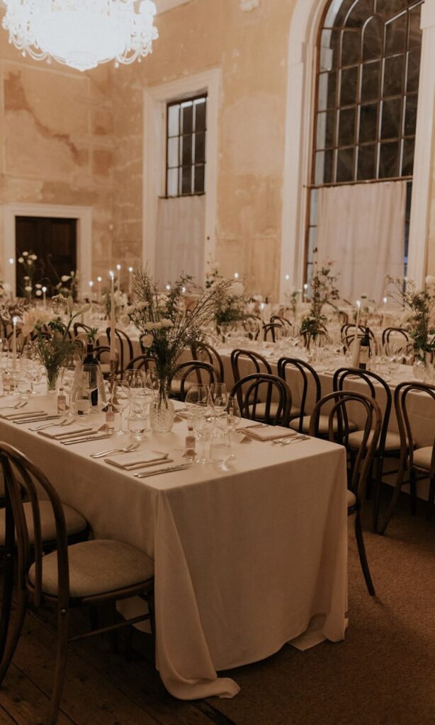 Elegant long tables adorned with white floral arrangements and candles set up in the Great Hall