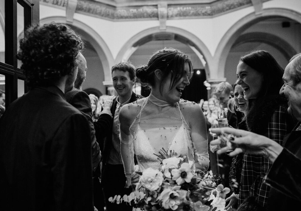 Clem and Finn arriving in the Octagonal Hall at Battersea Arts Centre, greeted by a confetti welcome from their guests.