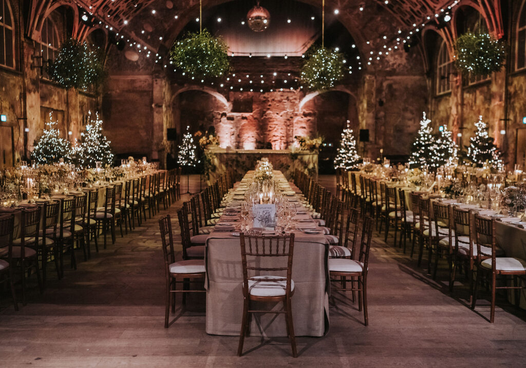 A wide-angle view of the grand dining room at Battersea Arts Centre, adorned with Christmas trees and mistletoe chandeliers hanging from the vaulted ceilings.