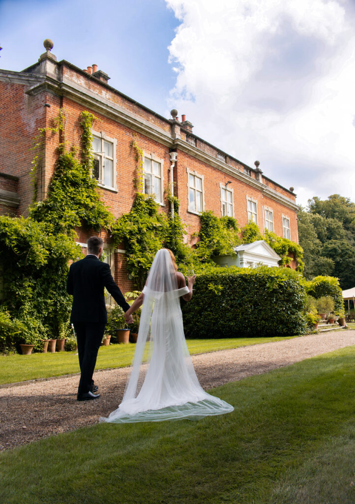 Couple Walking Through the Grounds:
“Bride and groom walking hand-in-hand through the scenic grounds of Green gate weddings, surrounded by lush greenery and natural beauty.