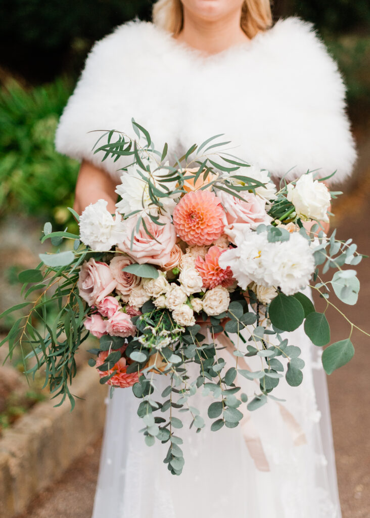 Bride holding an elegant bouquet at Weddings, featuring a blend of seasonal flowers in soft pastel tones.