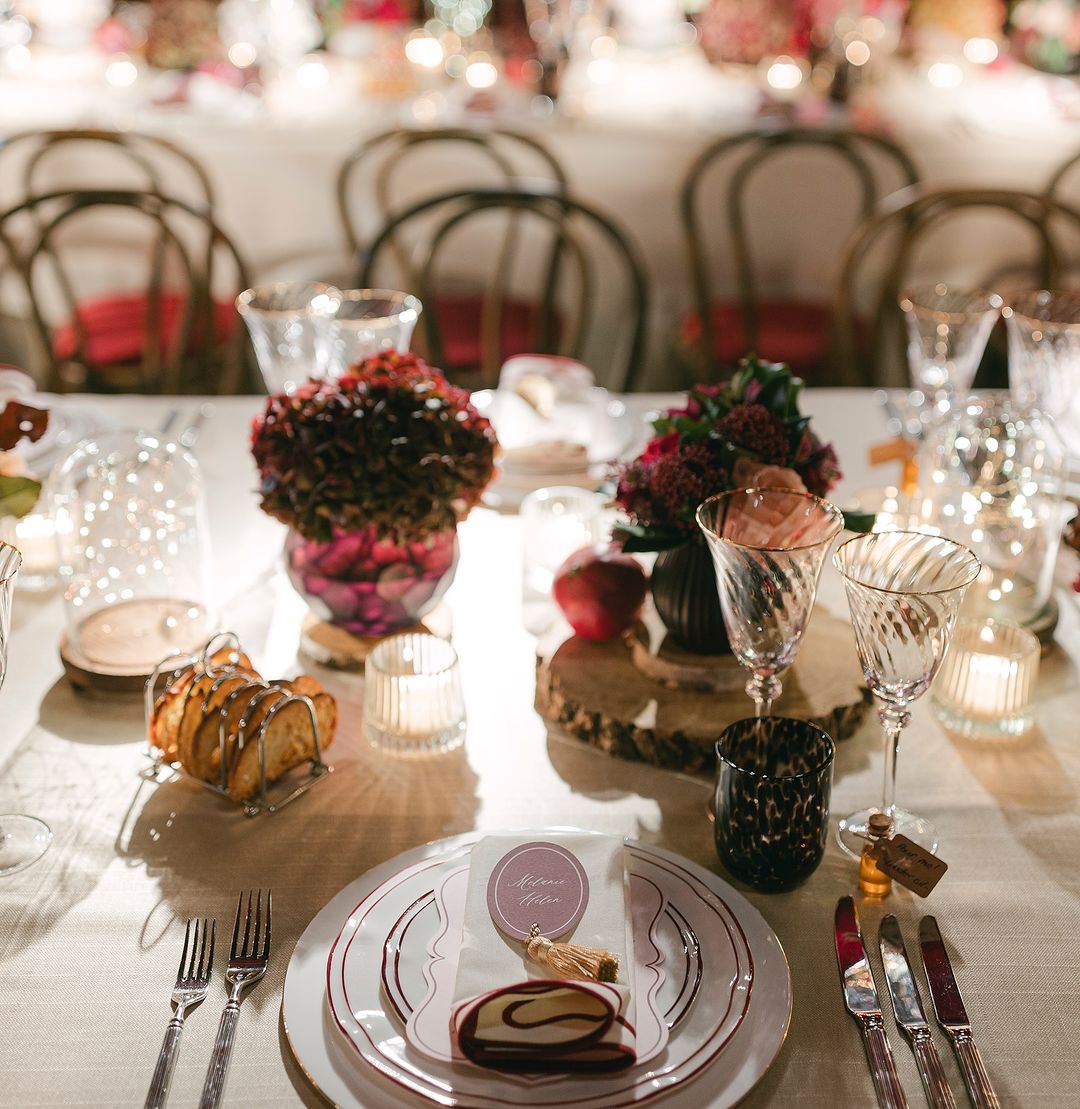 A wide-angle view of a lavish dinner setup at Two Temple Place, with long banquet tables adorned with floral centerpieces, gold candelabras, and soft, romantic lighting.