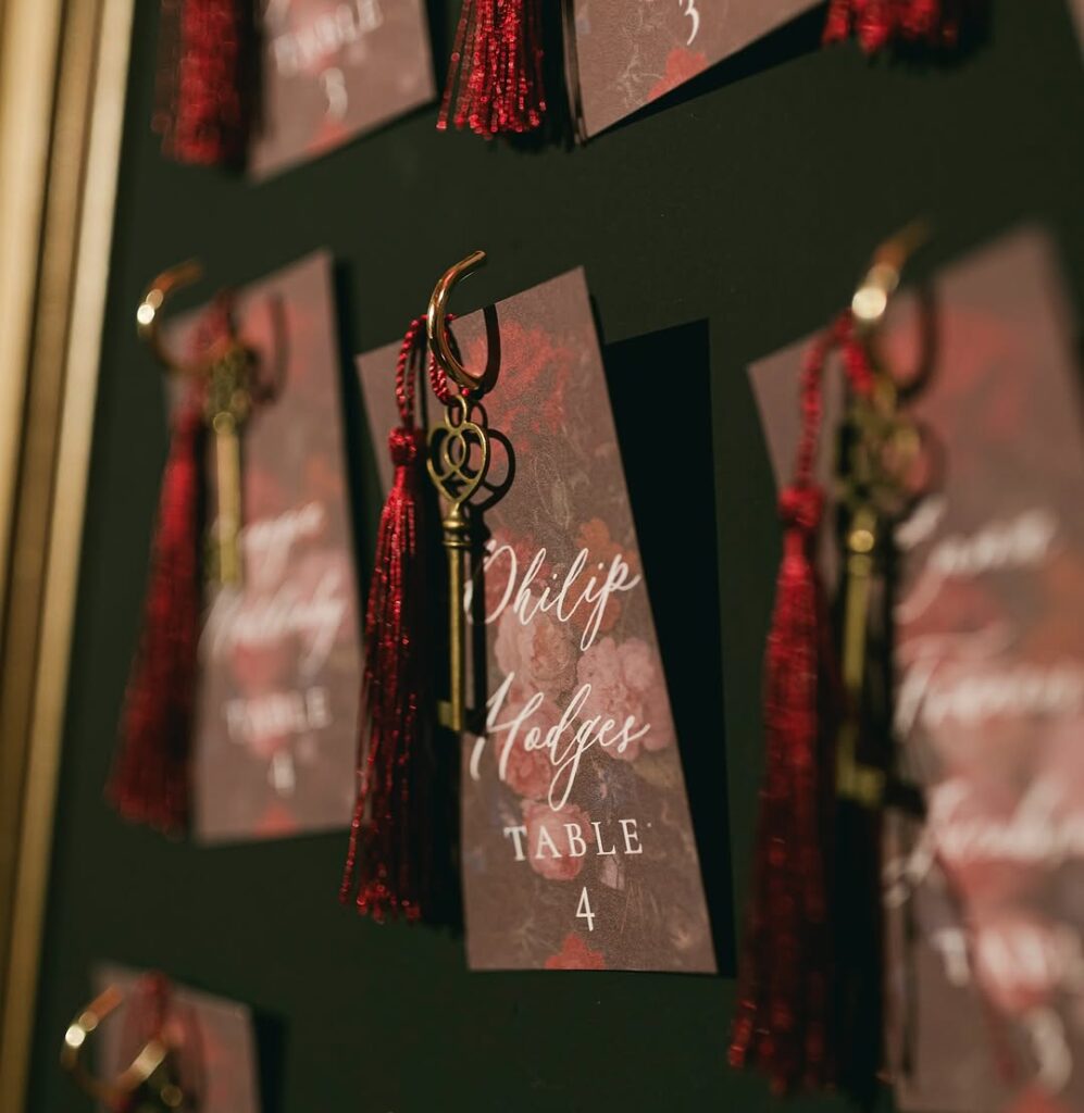  A close-up of name cards from the seating chart of Two temple place, featuring elegant red tassels and gold keys, adding a touch of charm and whimsy to the event decor.