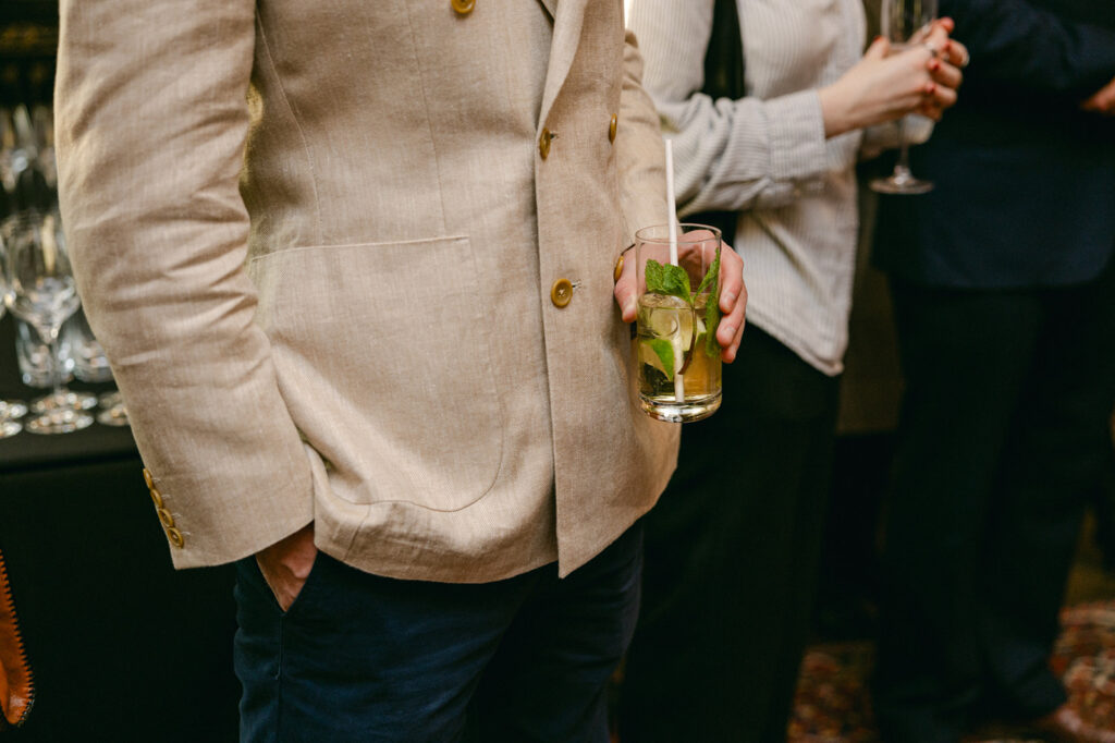 Guest in linen jacket holding a cocktail during the Where Snowbirds Play book launch at Leighton House