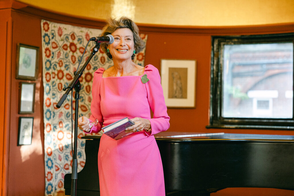 Gina Goldhammer smiling on stage at Leighton House during her Where Snowbirds Play book launch